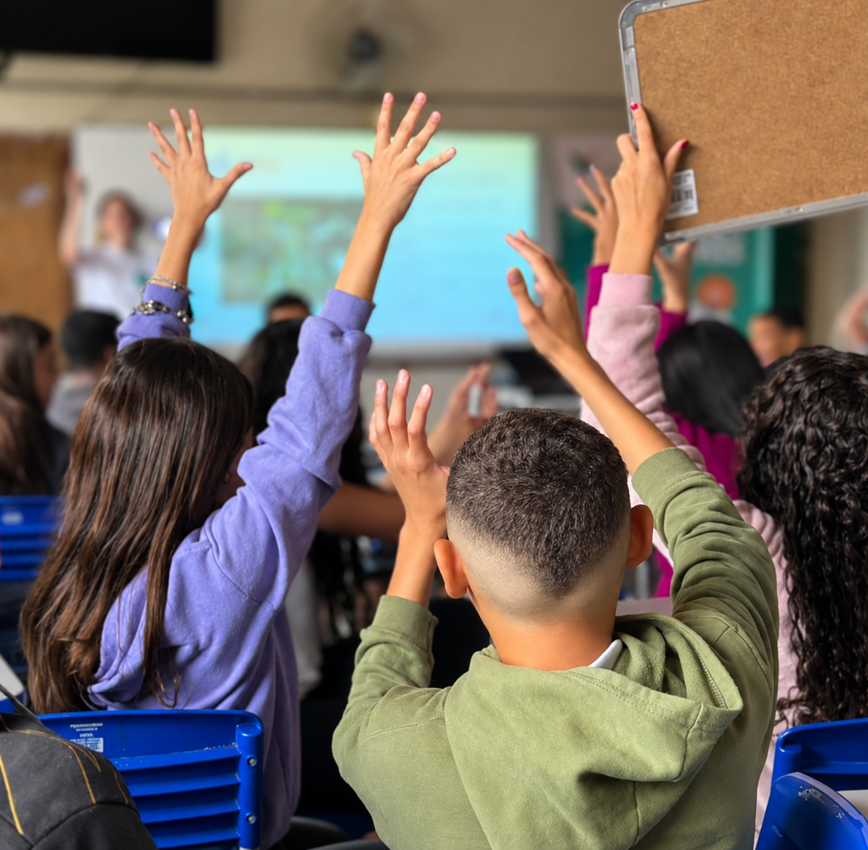 Estudantes com as mãos levantadas em sala de aula